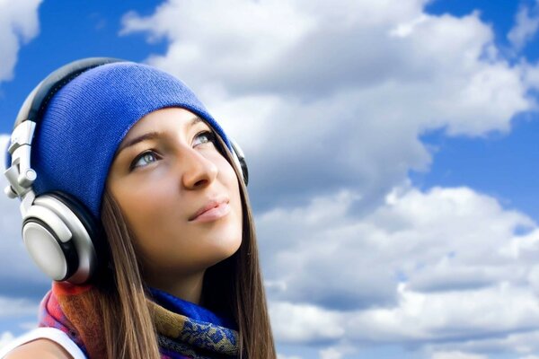 A girl in a blue cap listens to music with headphones