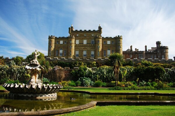 Castle with fountain and pond on blue sky background