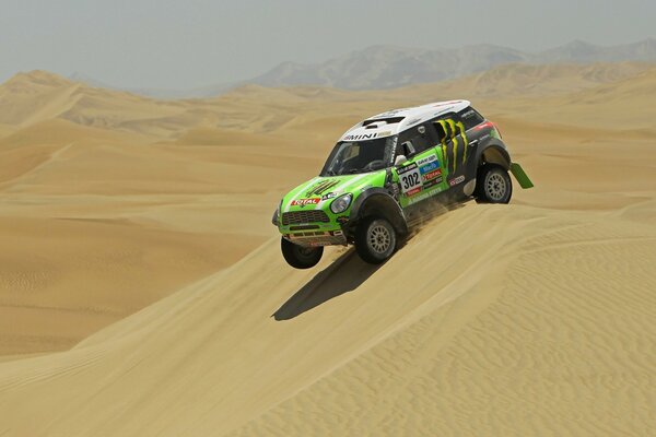 A racing car overcomes a sand dune