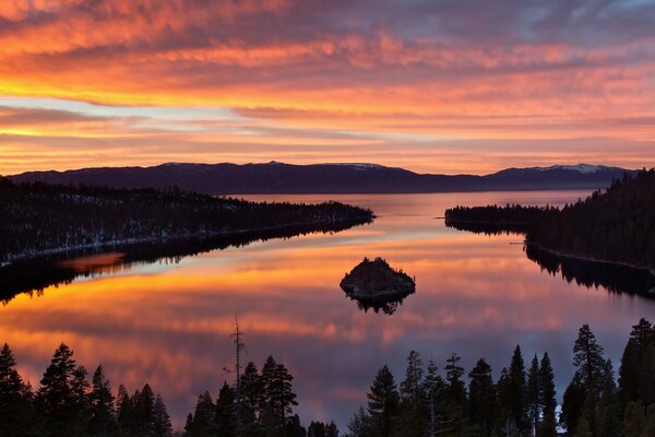 Schöner Sonnenuntergang über einem See in der Mitte der Taiga, in dessen Mitte sich eine kleine Insel befindet