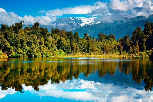 Forêt, montagnes et nuages se reflètent dans le lac