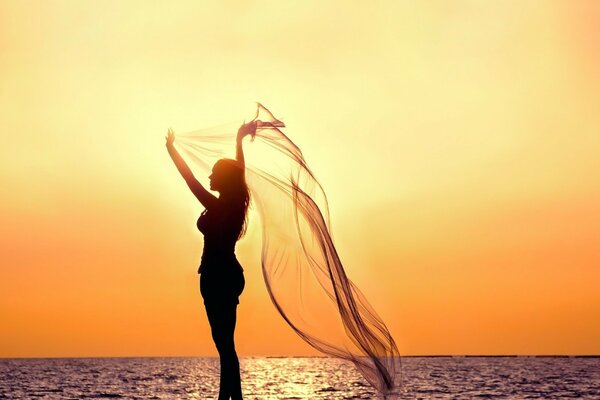 Fille au bord de la mer sur fond de coucher de soleil