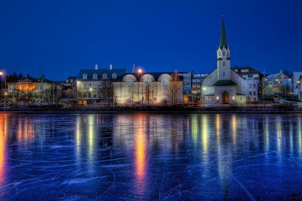 Rivière gelée avec une vieille ville nocturne sur le rivage