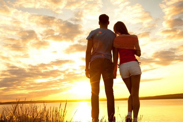 Lovers at the lake admire the sunset