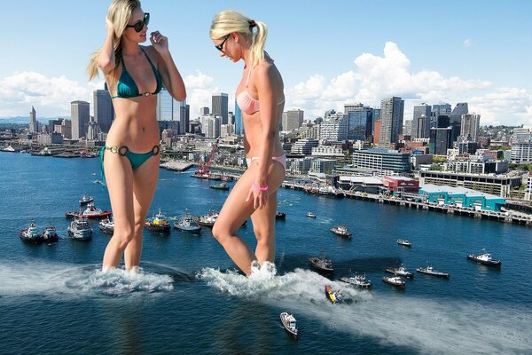 Dos hermosas chicas en trajes de baño en el fondo del mar con barcos y la costa construida