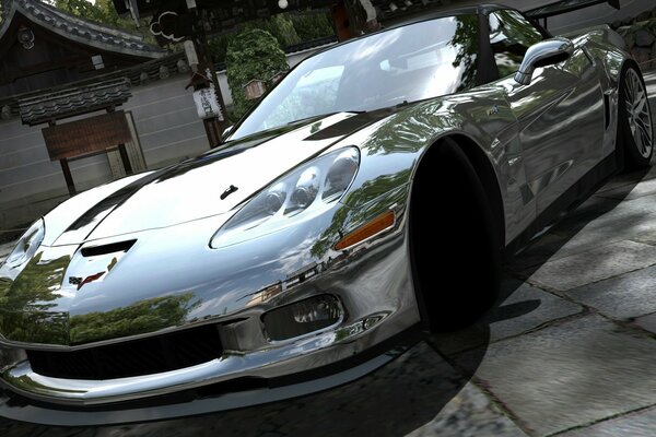 A sporty shiny car on the street near a small building