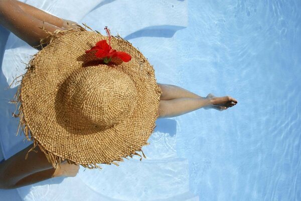 Fille au chapeau en vacances dans la piscine