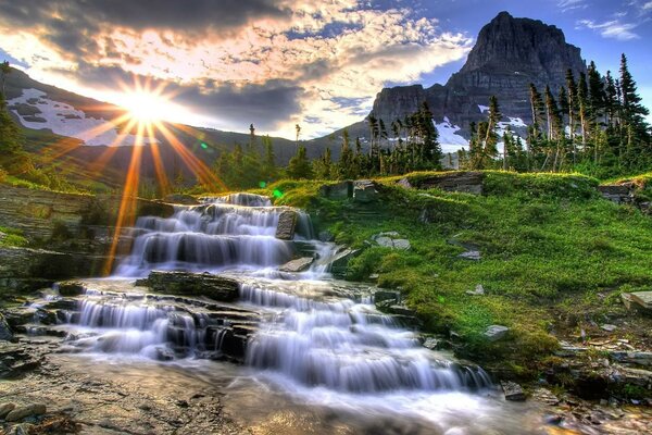 Landschaft mit Bergen, Bäumen und einem Wasserfall