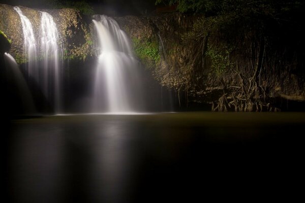 Paisaje cascada que desemboca en el río por la noche