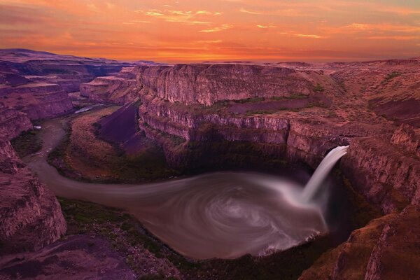 Sunset on a canyon with a waterfall and a river