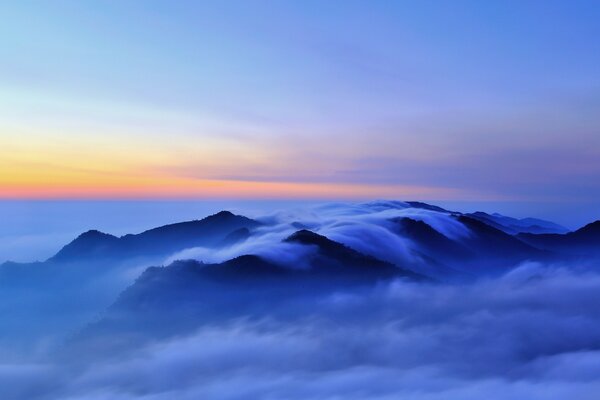 Mountain peaks in clouds at sunset