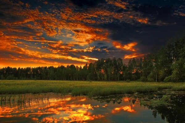 The fiery sunset is reflected in the water surface of the lake