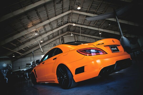 Coche deportivo Mercedes de color naranja en el hangar