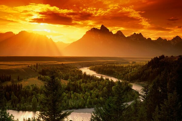 Pôr do sol de fogo sobre a floresta e o rio