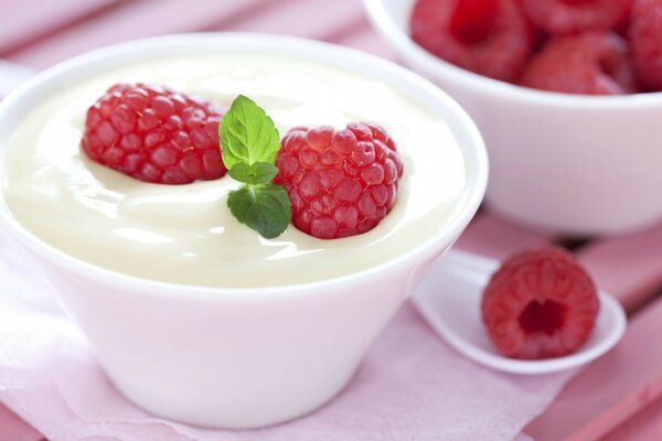 A cup of creamy dessert with raspberries