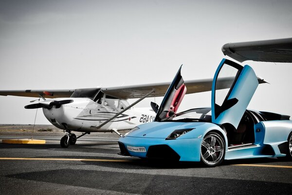 A blue car next to a white plane