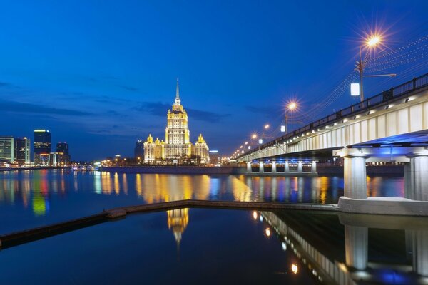 Архитектура ночного города с длинным мостом над водной гладью