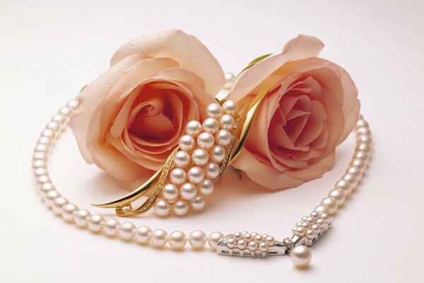 A necklace of pearls lies on the roses