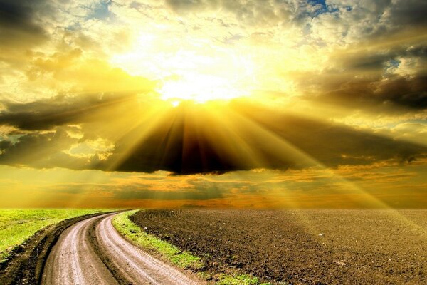 The rays of the sun through the clouds illuminate the road