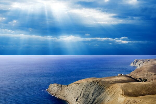 Die Sonnenstrahlen brechen durch die Wolken über dem Meer