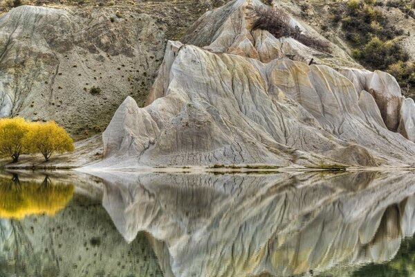 Gelbe ha-Bäume im Hintergrund der Berge spiegeln sich im Wasser wider