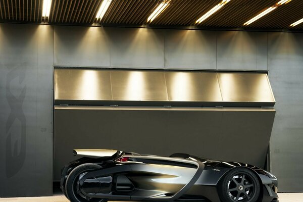 A black sports car in the premises of an elite garage is consecrated with lamps