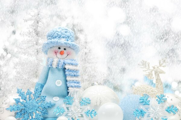 A white snowman in blue clothes next to a white deer and white blue balls and snowflakes