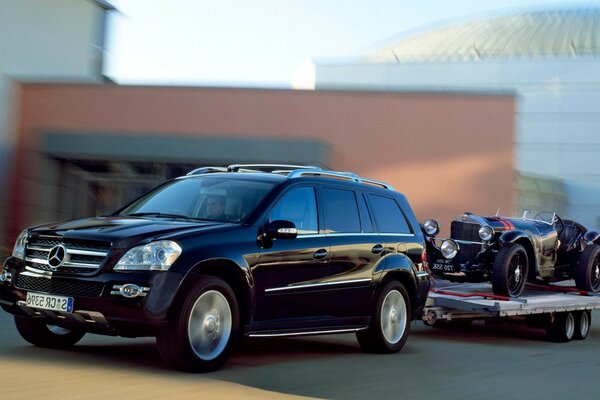 Mercedes noire avec une remorque dans laquelle se trouve une Rétromobile