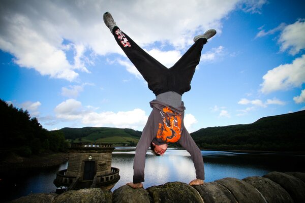 Tracer performs a handstand on the wall near the lake