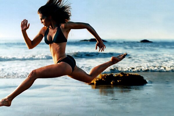 A girl runs along the coast of the sea