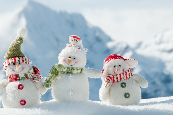 Three snowmen on the background of mountains