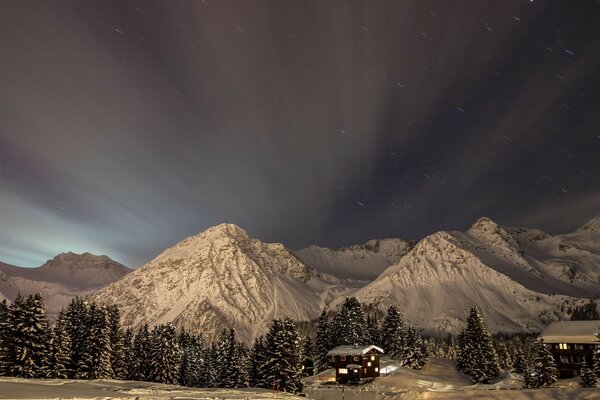 Foresta invernale con montagne. case vicino alle montagne. paesaggio invernale