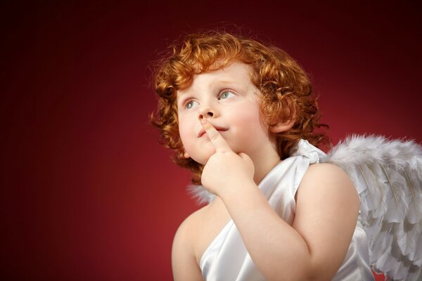 A child with curly red hair in the image of an angel