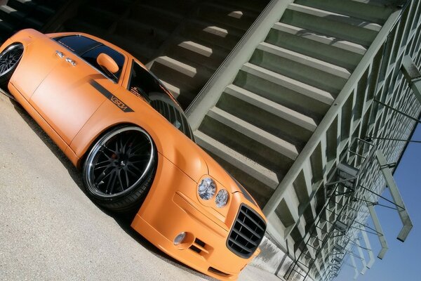 Coche Premium naranja en el fondo de un edificio de concreto