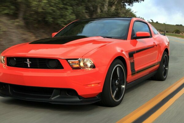 A sporty red car is racing along a mountain highway