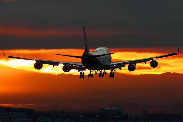 Landendes Flugzeug im Hintergrund des Sonnenuntergangs