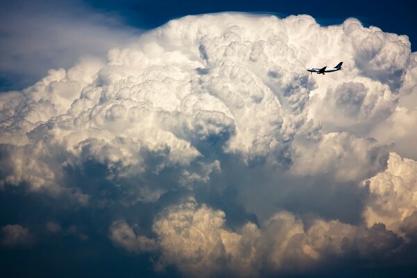 A plane flying past white clouds