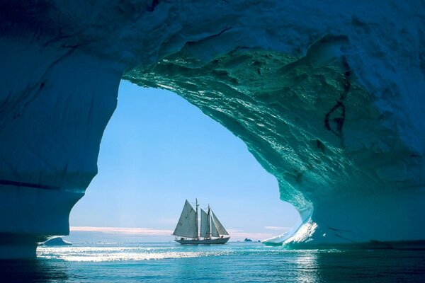 Velero en el océano bajo las bóvedas de los acantilados