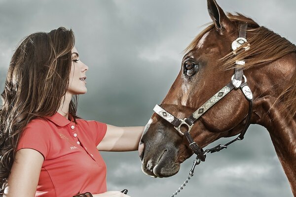 Ritratto di una ragazza con un cavallo su uno sfondo di cielo grigio