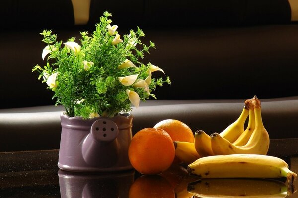 Bananes et oranges sur la table avec des fleurs