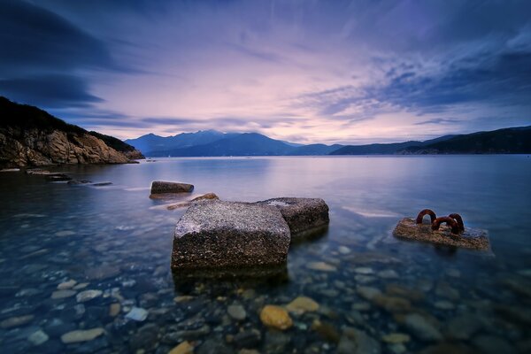 There are boulders and rocks in the water near the beach