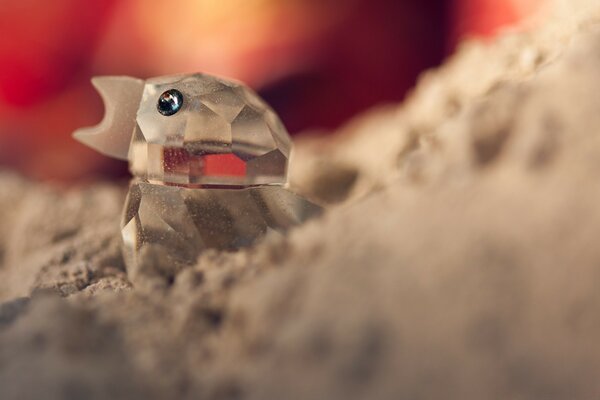 Un poussin de verre craque dans le sable