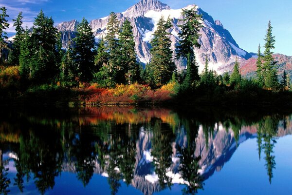 Montanha coberta de neve, lago entre a floresta