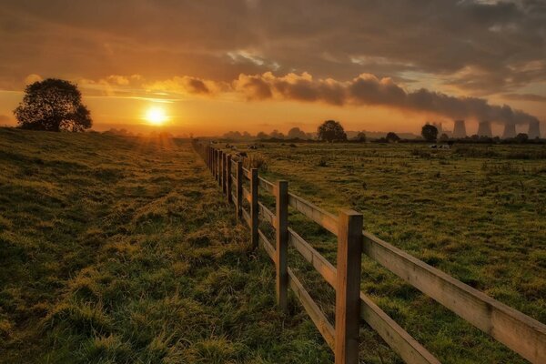 Ein Zaun, der die Weide von wilden Tieren abgrenzt. Sonnenuntergang der Sonne