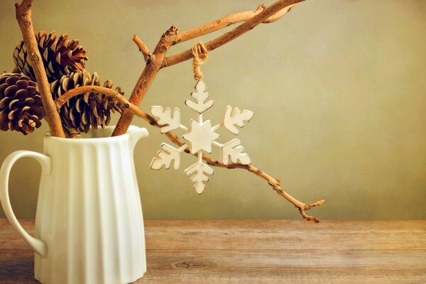 Nature morte avec des brindilles dans une cruche, des cônes de sapin et un flocon de neige