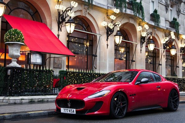 A red maserati parked outside a cafe