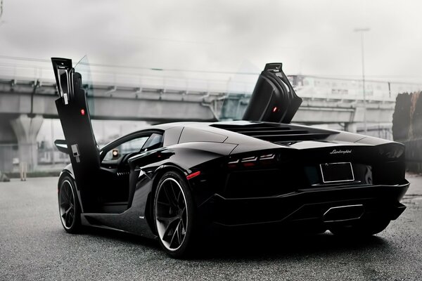 Un Lamborghini deportivo negro sobre un fondo urbano gris