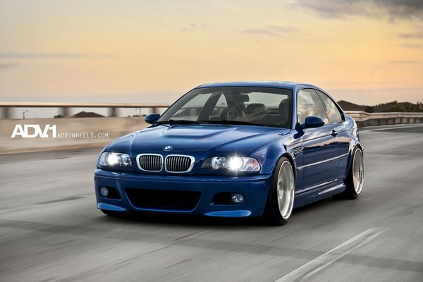 A blue BMW is moving along the autobahn