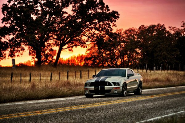 O carro anda na estrada ao pôr-do-sol