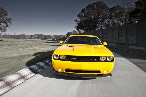 A bright yellow car is driving on the highway